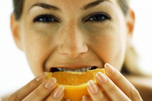Woman biting into orange slice