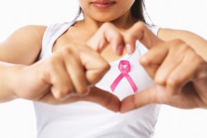 Heart framing on woman chest with pink badge to support breast c