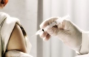 Physisian giving injection into arm of boy (5-7), side view, close-up