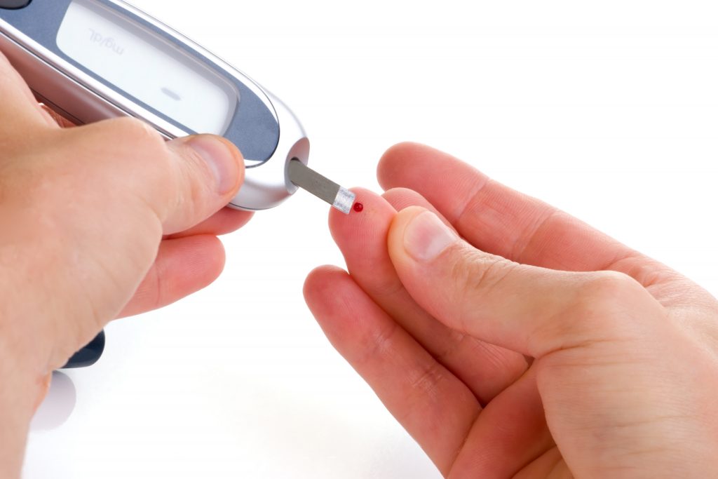 Diabetic is doing a glucose level finger blood test.