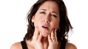 BRTAMY Beautiful young attractive woman with dental tooth jaw pain expression feeling unwell, holding her chin, isolated.