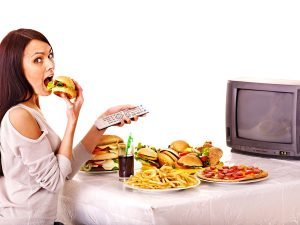 Woman eating fast food and watching TV.