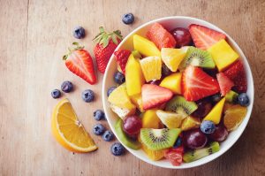38570258 - bowl of healthy fresh fruit salad on wooden background. top view.