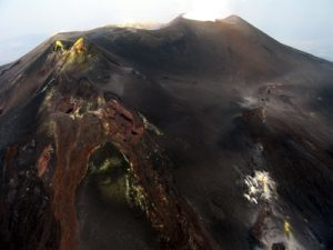 Visione aerea, da Est, dell’area sommitale dell’Etna. A sinistra, si nota il cono del Cratere di Sud-Est, “bucato” in corrispondenza della sua base orientale dalla bocca eruttiva che costruirà, dal 2011 in poi, il Nuovo Cratere di Sud-Est. A destra, si osserva la frattura eruttiva che ha alimentato l’eruzione laterale del 2008-2009. Foto: Marco Neri