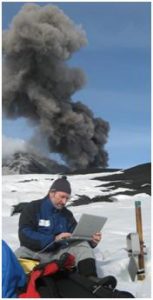 Stazione di misura dei dati Radon collocata nel sito di Torre del Filosofo (fianco Sud dell’Etna, quota 3000 circa). Sullo sfondo si nota la contemporanea attività eruttiva a circa 1 km di distanza dalla stazione di monitoraggio. Foto di M. Neri