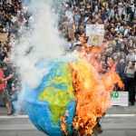 Protestano contro le emissioni di anidride carbonica e bruciano una Terra di carta emettendo anidride carbonica