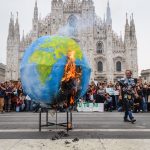 Protestano contro le emissioni di anidride carbonica e bruciano una Terra di carta emettendo anidride carbonica