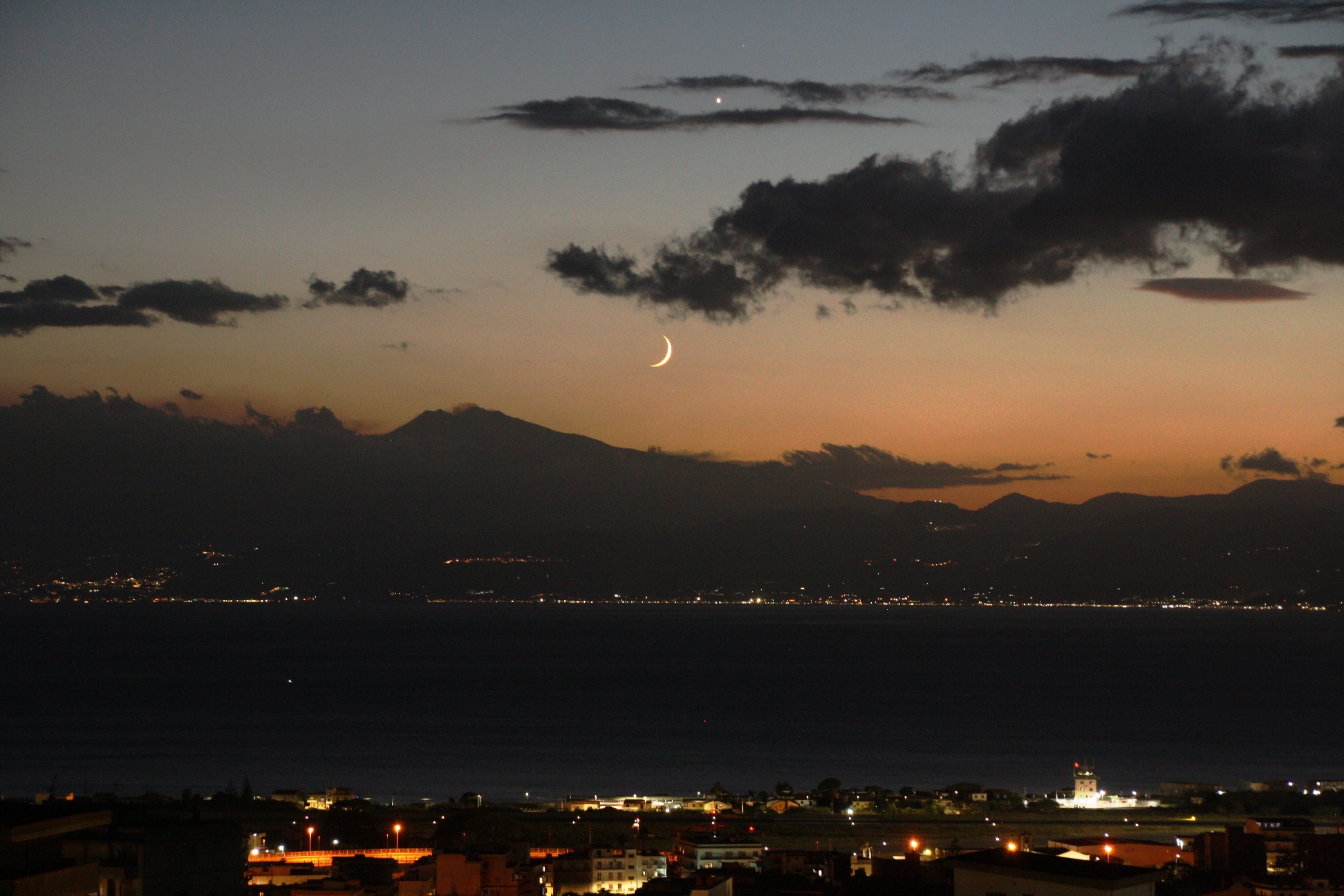 La falce di Luna e Venere al tramonto sull’Etna: grande spettacolo nello Stretto di Messina | FOTO